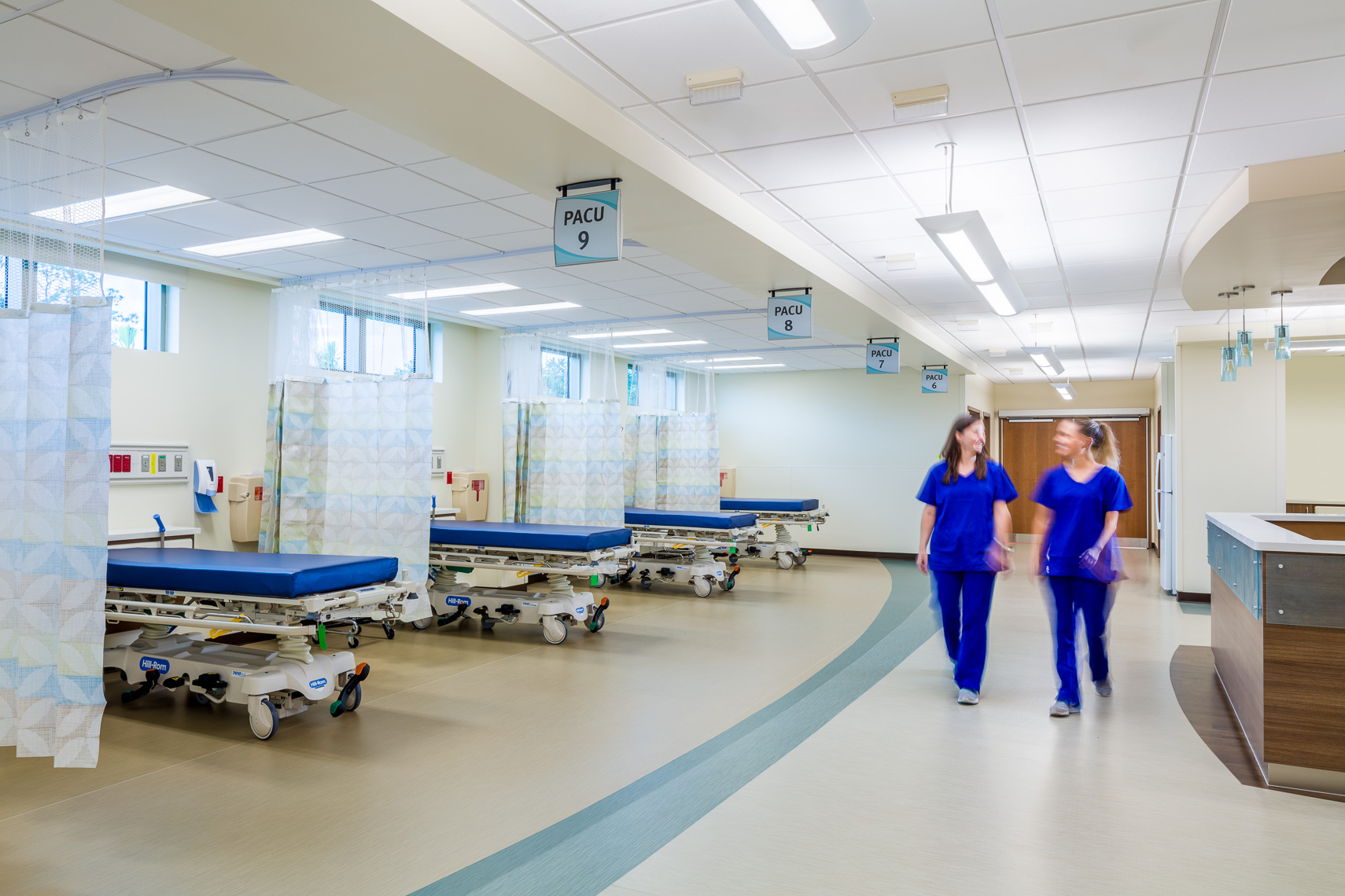 Two nurses walk through a hospital room